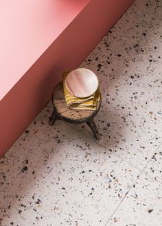 a chair with a shell on it sitting in front of a pink wall