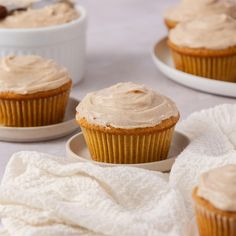 three cupcakes with frosting sitting on top of white plates and napkins