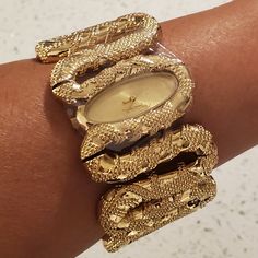 100% Authentic Poshmark Will Authenticate Over $500 Roberto Cavalli Cleopatra Women's Gold Tone Snake Bracelet Watch New With Tags, Includes Box Brushed Gold Tone Oval Analog Face Polished Gold Tone Snake Form Hour And Minute Hands Roberto Cavalli Logo At The 12 O'clock Position Gold Tone Stainless Steel Fixed Bezel Stainless Steel Case Back Polished Gold Tone Raised Texture Stainless Steel Bangle Style Watch Band Push Action Inset Closures Fast Shipping! New To Poshmark? Use Referral Code Mibel High Jewelry Gold, Ghanaian Gold Jewelry, Gold Bangles Black Women, Roberto Cavalli Jewelry, Gold Wire Wrapped Jewelry, Unique Bracelet Design For Women, Gold Snake Bracelet, Gold Earthy Jewelry, Stacked Watches