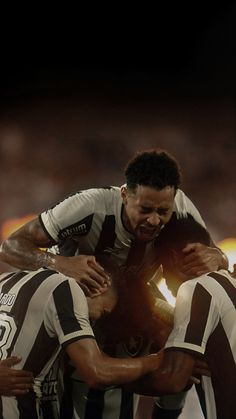 two soccer players are hugging each other in the middle of a huddle on their knees