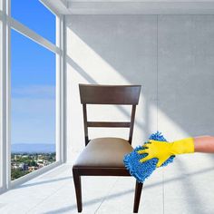 a person cleaning a chair with a mop and yellow rubber glove on their hand