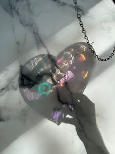 a person is holding onto a disco ball on a chain that's attached to a marble surface