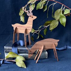 three wooden deer figurines sitting on top of books with leaves and ribbons around them