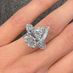 a woman's hand with a large diamond ring on it and the center stone is surrounded by smaller diamonds