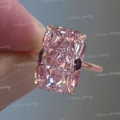 a pink diamond is being held up by someone's hand with the ring on it