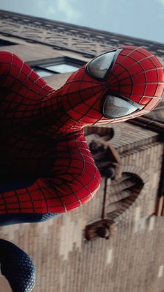 a close up of a spider man's face in front of a brick building