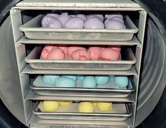 four trays filled with different colored candles on top of a metal rack in front of a stove