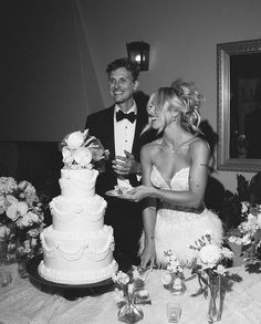 a man and woman standing next to each other in front of a cake