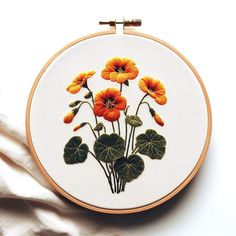 an embroidery project with orange flowers and green leaves