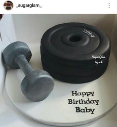 a birthday cake with a dumbble weight and happy birthday baby on the bottom layer