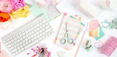 flowers, scissors and other crafting supplies are laid out on a desk top with a keyboard