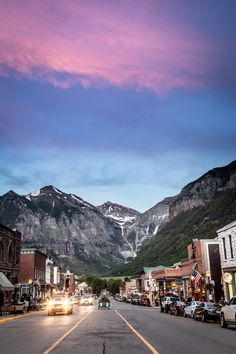 a street with cars parked on the side and mountains in the backgrouds