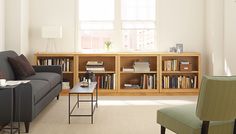 a living room filled with furniture and bookshelves next to a window covered in sunlight