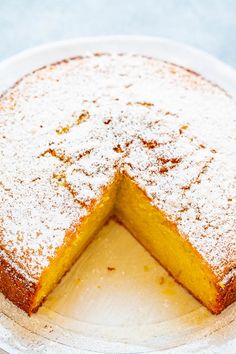 a cake on a white plate with one slice cut out and powdered sugar on top