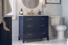 a white toilet sitting next to a blue vanity in a bathroom under a round mirror