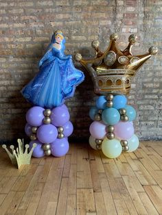 some balloons are stacked on top of each other in front of a brick wall with a gold crown