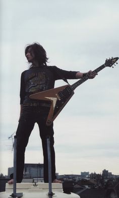 a man holding an electric guitar on top of a roof