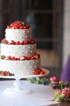 a three tiered white cake with strawberries on top