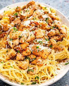 a plate of pasta with chicken and parmesan cheese on top, ready to be eaten