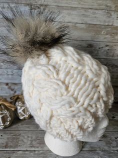 a white knitted hat with a fur pom - pom sitting on top of it