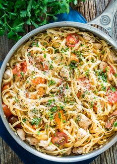 pasta with chicken, tomatoes and parmesan cheese in a pan on a wooden table