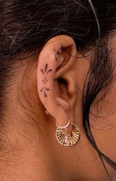 a woman's ear is adorned with tattoos