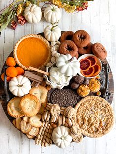 a platter filled with cookies, pies, and other foods on top of a wooden table