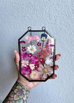 a person holding up a small mirror with flowers on it