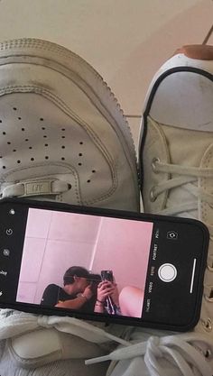 someone taking a photo with their cell phone while sitting on top of some shoes and sneakers