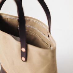 The Field Tan Canvas mini panel tote is a canvas and leather tote handmade in the KMM & Co. studio in Atlanta. Each one is meticulously crafted from heavyweight canvas and gorgeous full-grain leather. Field Tan Canvas is a type of cotton canvas known as duck cloth. It's one of the most durable types of cloth, and it's structured enough to stand up on its own. The Field Tan Canvas mini panel tote comes standard with Dark Brown handles and a Brown Kodiak bottom panel. (To customize the color of th Leather Canvas Crossbody Bag With Handles, Leather Crossbody Canvas Bag With Handles, Leather Canvas Bucket Bag With Leather Handles, Leather Bucket Canvas Bag With Leather Handles, Leather Canvas Crossbody Bag With Top Carry Handle, Leather Crossbody Bag With Top Carry Handle, Leather Canvas Bag With Canvas Lining For On-the-go, Duck Cloth, The Field