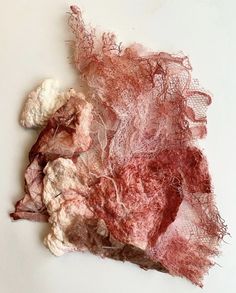 a piece of red and white yarn sitting on top of a white table next to a pile of rocks