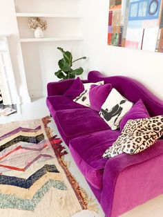 a purple couch sitting in the middle of a living room next to a white wall