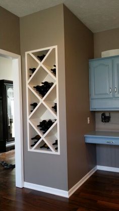 an empty kitchen with blue cabinets and wood flooring in the center, along with a wine rack on the wall