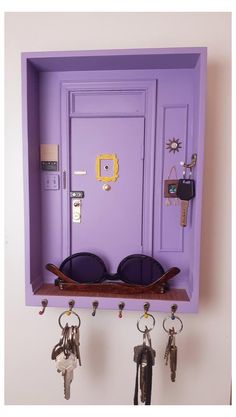 a purple door with sunglasses and keys hanging from it's sides on a wall