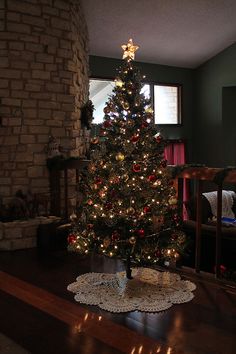 a small christmas tree is lit up in the corner of a room with a fireplace