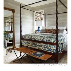 a bedroom with a four poster bed and mirror in the corner, along with a side table