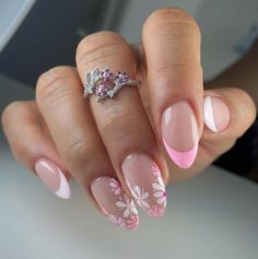 a woman's hand with pink and white flowers on it, holding a ring