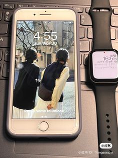 an apple watch sitting on top of a laptop computer next to a cell phone and keyboard