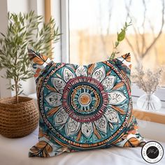 a decorative pillow sitting on top of a bed next to a potted plant and window