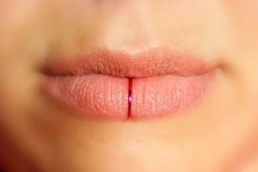 a woman's lips with a red line on the tip of her lip in front of her face