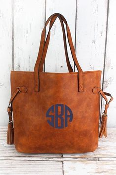 "Side Tassel Purse Material: Vegan Leather 2 Tassels One on Each Side 1 Inside Zipper Money Pocket Open Top (No Zipper Closure) Plenty of interior Space for all sized Items Shoulder Strap: 8\" Dimensions: Approx. 16\"(L) x 3.5\"(W) x 11.5\"(H) These bags are monogram-ready, and make the perfect gift for friends, family, teachers, or any loved one. ---PLACING AN ORDER--- - Choose your Personalization Style from the drop-down menu.  - During Checkout include \"Notes to Seller\" (box at bottom) wit Brown Tassel Bags For Shopping, Brown Tasseled Bags For Shopping, Brown Shopping Bags With Tassels, Diy Leather Tote, Tassel Purse, Leather Storage, Monogram Tote Bags, Faux Leather Purse, Diy Handbag