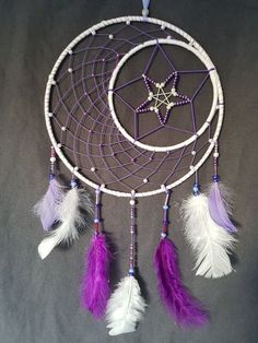 a purple and white dream catcher with feathers