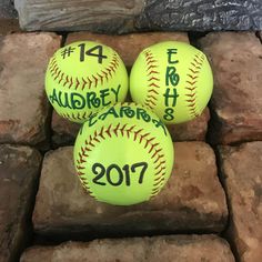 three yellow softballs with numbers on them sitting on some bricks and brick pavers