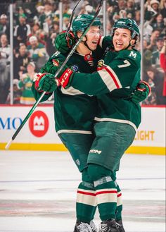 two hockey players hugging each other on the ice