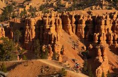 a person riding a bike on a trail in the middle of some rocks and trees