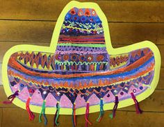 a paper cutout of a colorful hat hanging on a wall with tassels