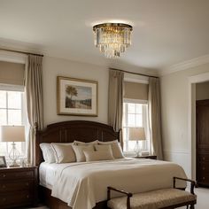 a bedroom with a large bed and chandelier hanging from it's ceiling