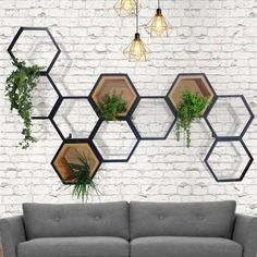 a couch sitting in front of a white brick wall with hexagonal planters on it