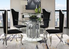 a glass dining table with black chairs and a vase on top of it in front of a cityscape