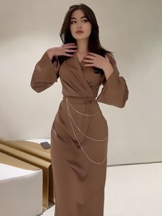 Thoughtfully designed to exude elegance, this taupe dress is a celebration of modern femininity. With voluminous bishop sleeves and a plunging neckline, it strikes a balance between bold and demure. The dress cinches at the waist with a unique chain detail, creating a flattering silhouette that accentuates the natural curves. Crafted from a sumptuous fabric with a hint of sheen, this piece is perfect for those who seek a blend of contemporary design and timeless appeal. Seasons: Spring/Autumn Ty Socialite Style, Taupe Dress, Rhinestone Chain, Satin Maxi, Satin Maxi Dress, Long Red, Looks Chic, Style Maxi Dress, Waist Dress